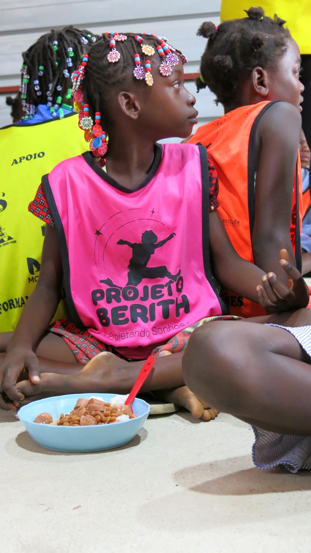 Criança da comunidade do Camassa durante a refeição, com colete do Projeto Berith